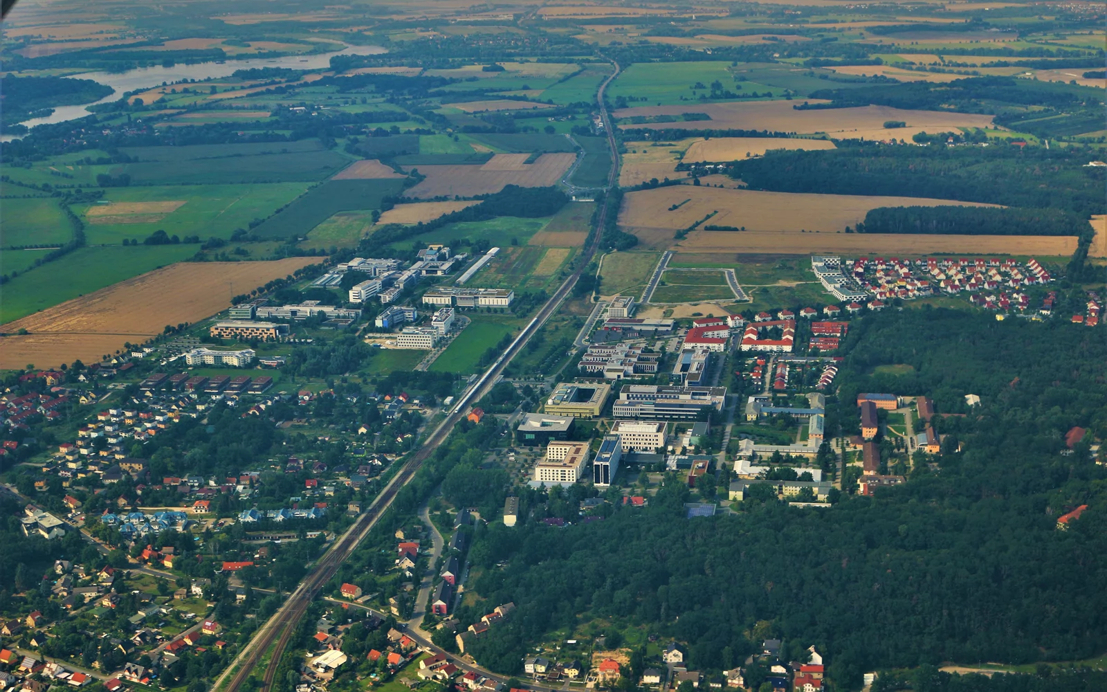 Flyfoto av et universitetsområde mellom boligstrøk, skog og jordbruksarealer.