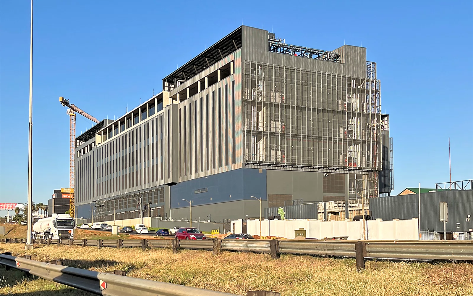 Stor bygning under oppføring, med byggekran og anleggsområde rundt.