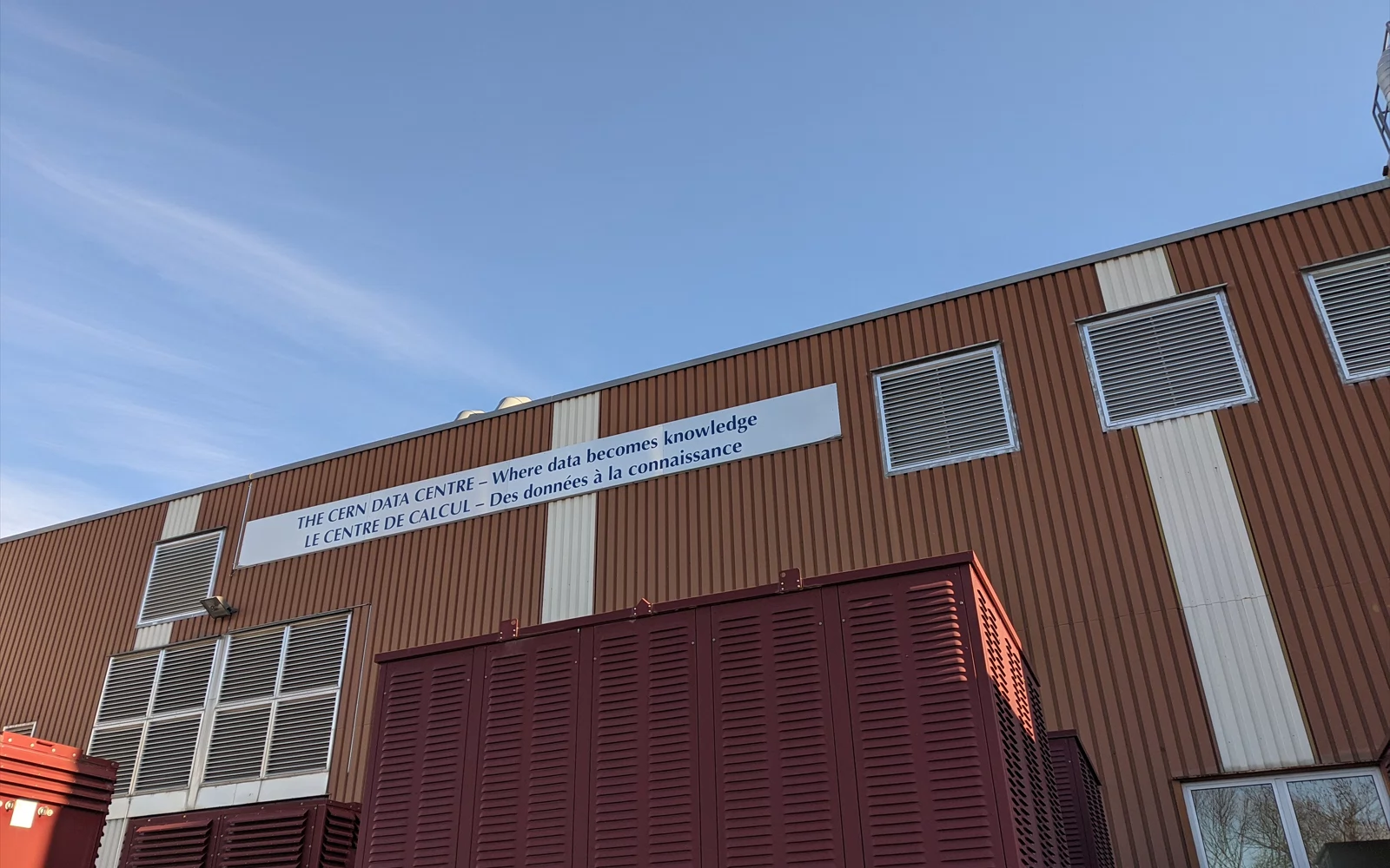 Teknisk bygning med ventilasjonsrister og skilt for CERNs datasenter.