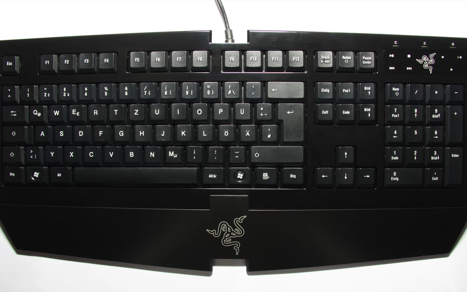 Svart tastatur med tallfelt og bred håndleddsstøtte på lys bakgrunn.