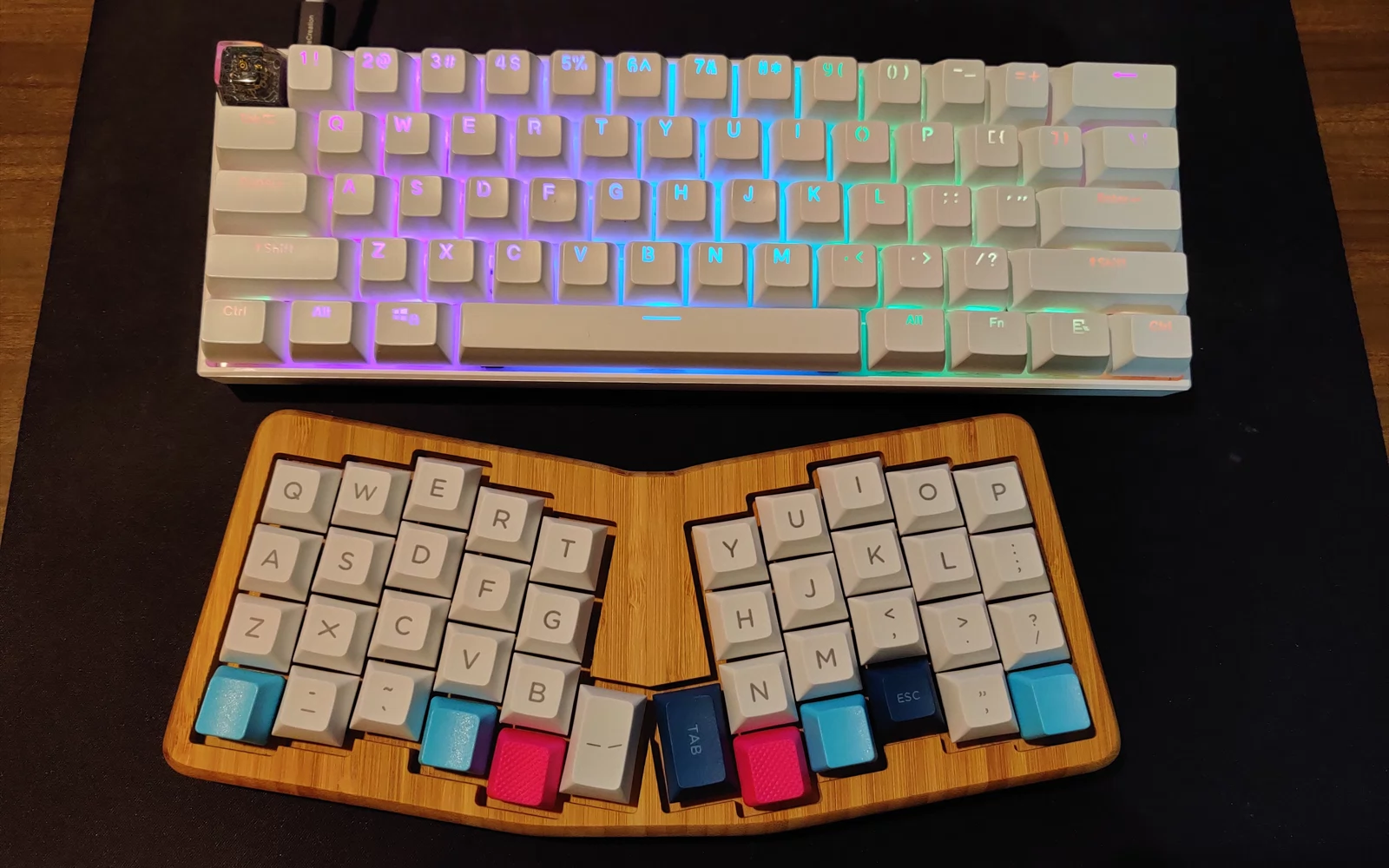 To kompakte tastaturer på mørkt underlag, ett med belysning og ett i trekabinett.